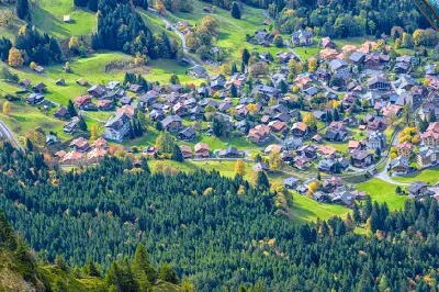 High-angle view over Wengen village with clustered chalets and surrounding forested slopes seen from Männlichen, Switzerland.