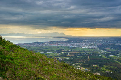 Elevated landscape view from Sir Lowry’s Pass overlooking False Bay, Somerset West, and the Cape Peninsula beneath dramatic winter storm clouds in the Western Cape, South Africa.