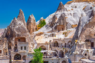 Fairy chimney rock formations with cave hotels and historic stone buildings in Göreme Town, Cappadocia, Turkey.
