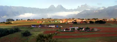 Morning mist below the Cathedral Range in the central Drakensberg with rural settlements in the foreground, KwaZulu-Natal, South Africa.
