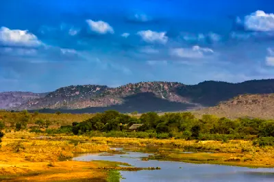 The Crocodile River near Malelane Gate in southern Kruger National Park with bushveld vegetation, distant hills and dramatic storm clouds overhead.