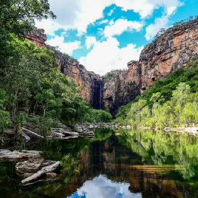 Sandstone cliffs and tropical forest reflected in the still plunge pool beneath Jim Jim Falls in Kakadu National Park, Northern Territory, Australia.