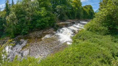 Elevated view of cascading waterfalls flowing over limestone steps along the River Ure at Aysgarth Falls in the Yorkshire Dales, England.