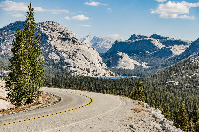 Winding Tioga Road above Tenaya Lake with granite domes and forest at Olmsted Point in Yosemite National Park.