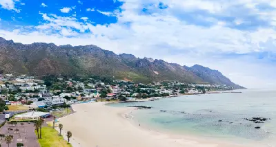 Aerial view of Gordon's Bay showing sandy beaches, turquoise water, coastal town and mountain backdrop along False Bay.