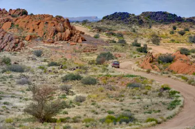 Gravel road winding through granite hills and semi-desert vegetation in Augrabies National Park, Northern Cape.