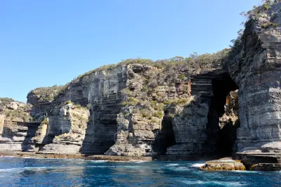 Sea-level view of Tasman Arch and towering layered cliffs on the Tasman Peninsula, Tasmania.