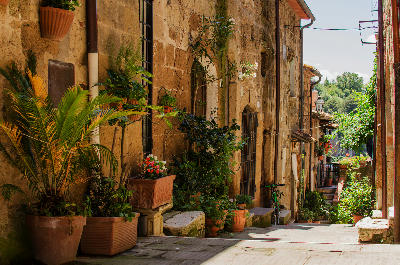 Flower-filled stone alley in the historic centre of Pitigliano, Tuscany, Italy.