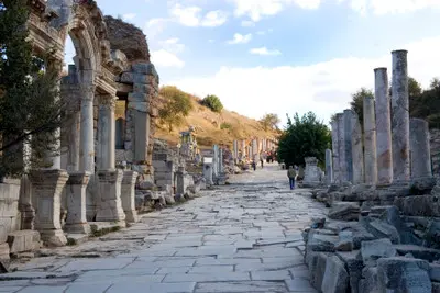 Marble-paved Curetes Street in Ephesus with rows of ancient columns and ornate ruins lining the historic thoroughfare.
