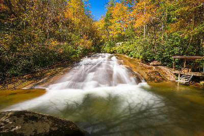 Long exposure view of Sliding Rock waterfall flowing through autumn forest in Pisgah National Forest, North Carolina.