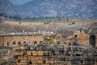 Ancient Roman theatre at Hierapolis, with tiered stone seating and ruins against the mountains near Pamukkale, Turkey.