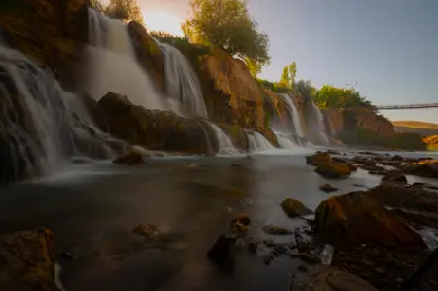 Long-exposure view of Muradiye Waterfall cascading over rocky cliffs in golden evening light in Van Province, Turkey.