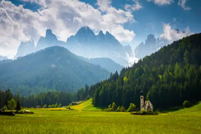 Santa Maddalena Church set in green fields in Val di Funes, with the Geisler (Odle) mountain range in the Dolomites behind, Italy.
