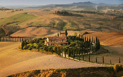 Cypress-lined farmhouse in the rolling hills of Val d'Orcia, Tuscany, Italy.