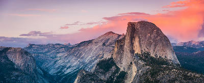 Half Dome from Glacier Point Yosemite with granite dome and layered mountain ridges under pink sunset sky.