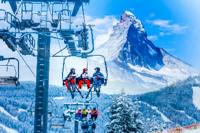 Skiers on chairlift with the Matterhorn in the background near Zermatt, Switzerland.