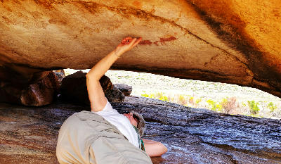 Visitor examining San rock art painted beneath a sandstone overhang along the Sevilla Rock Art Trail at Traveller’s Rest in the Cederberg Mountains, Western Cape, South Africa.