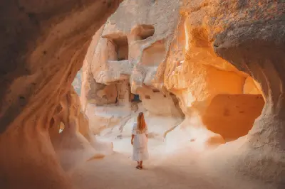 A traveler standing inside the rock-cut cave dwellings of Paşabağ (Monks Valley), surrounded by sculpted volcanic tuff formations and ancient chambers in Cappadocia, Turkey.