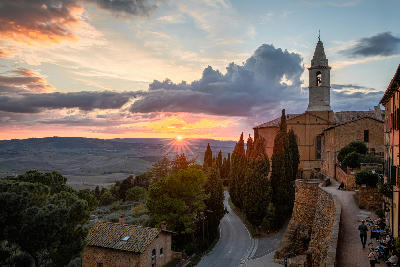 Autumn sunset over the historic town of Pienza in Tuscany, with the Val d'Orcia hills stretching into the distance. The warm evening light illuminates the church and surrounding cypress trees .Pienza, a UNESCO World Heritage site, is known for its stunning landscapes and Renaissance architecture.
