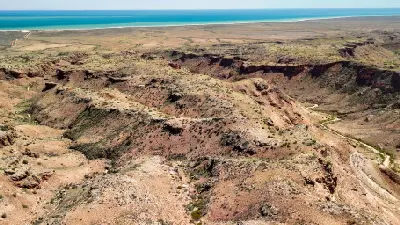 Aerial view across the rugged gullies of Charles Knife Canyon towards the turquoise Indian Ocean.