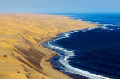 Aerial coastline of large Namib Desert dunes meeting the Atlantic Ocean on Namibia’s Skeleton Coast.