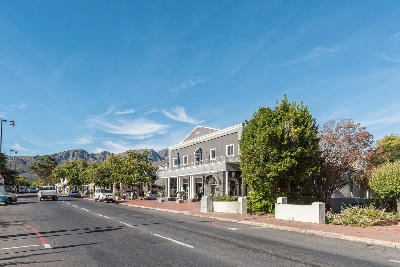 Franschhoek Village main street with boutique storefronts and mountain backdrop in the Western Cape Winelands, South Africa.
