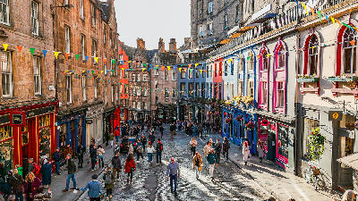 Victoria Street in Edinburgh with colourful buildings, cobblestones and pedestrians.