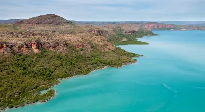 Turquoise waters surround the rugged sandstone coastline and native vegetation of Naturalist Island in Prince Frederick Harbour.