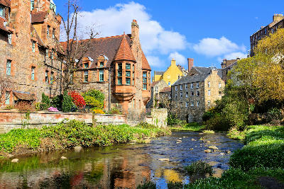 Dean Village in Edinburgh, Scotland, with historic buildings reflected in the calm waters of the Water of Leith.