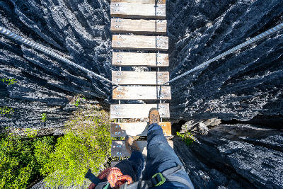Hiker crossing a suspension bridge above the limestone pinnacles of Tsingy de Bemaraha, Madagascar