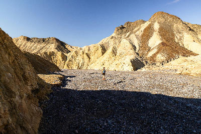 Hiker walking through Golden Canyon in Death Valley National Park California with yellow badlands walls and open canyon floor