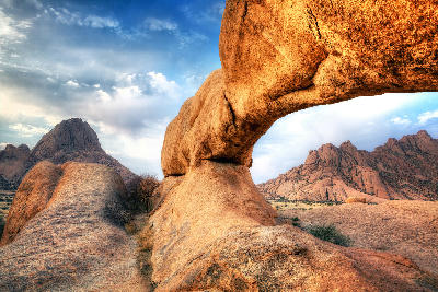 Natural granite arch in the Spitzkoppe landscape with rocky desert formations under dramatic skies in Namibia.