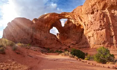 Double Arch sandstone formation with approach path and desert terrain in Arches National Park Utah