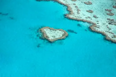 Aerial view of the heart-shaped Heart Reef surrounded by turquoise water and coral reef in the Great Barrier Reef, Queensland.