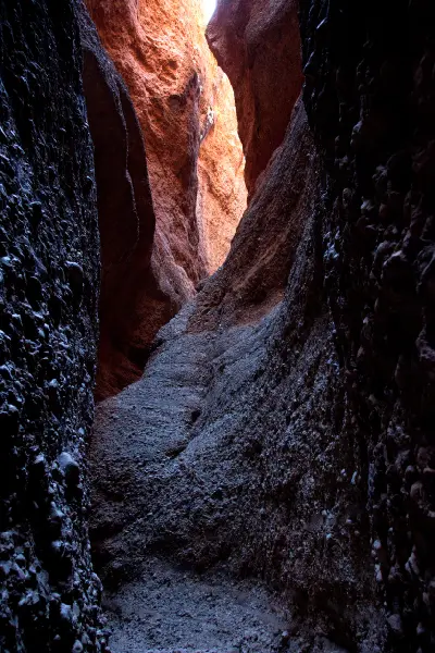 Sunlight catches the orange rock deep within the narrow, shadowed walls of Echidna Chasm in the Bungle Bungles.