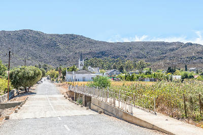 Road and church steeple in the small town of Barrydale surrounded by rugged hills in the Tradouw Valley of the Western Cape, South Africa.