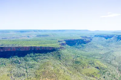 Broad aerial view across rugged escarpments, deep valleys and vast bushland in the East Kimberley landscape.