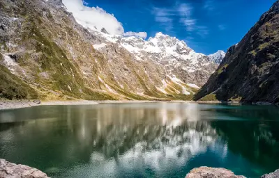 Lake Marian surrounded by steep snow-capped mountains in Fiordland National Park, South Island, New Zealand.