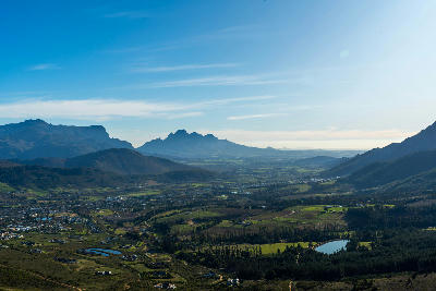 Bird’s-eye landscape view from Franschhoek Pass above Franschhoek Valley with vineyards, mountain ranges, and rural scenery in the Cape Winelands of South Africa.