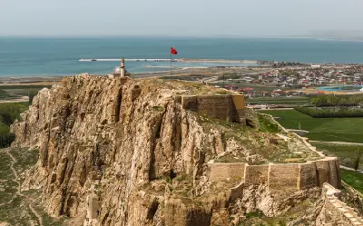 Aerial view of Van Castle on its steep rocky ridge overlooking the blue waters of Lake Van and the city of Van, eastern Turkey.