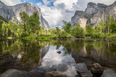 Reflections of granite cliffs and trees in the Merced River in Yosemite Valley, Yosemite National Park, California.