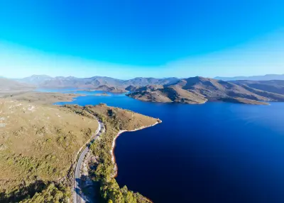 Aerial view of Lake Pedder and Gordon River Road surrounded by rugged mountains in Southwest National Park, Tasmania.
