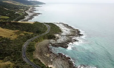 Aerial view of the Great Ocean Road curving beside rocky coastline and the Southern Ocean in Victoria, Australia.
