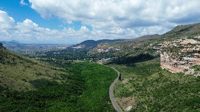 Aerial view of the road leading into Clarens between sandstone cliffs and mountain valleys in the Eastern Highlands of South Africa.