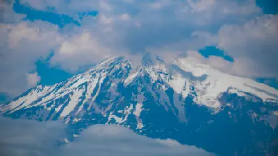 Telephoto view of the snow-covered summit of Mount Ararat partially shrouded in clouds, Eastern Turkey.