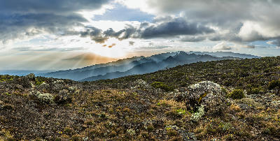 Sun rays breaking through dramatic clouds above Mount Meru, viewed from the Shira Plateau on Mount Kilimanjaro, Tanzania, at an altitude of approximately 3,800 metres above sea level.