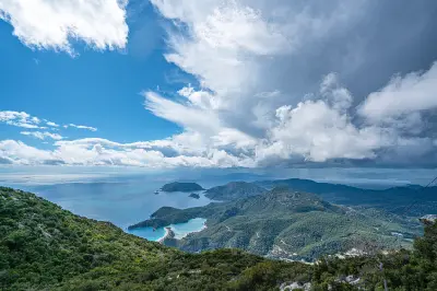 Panoramic view from Babadağ across forested mountains, the Blue Lagoon and Mediterranean coastline near Ölüdeniz, Türkiye.