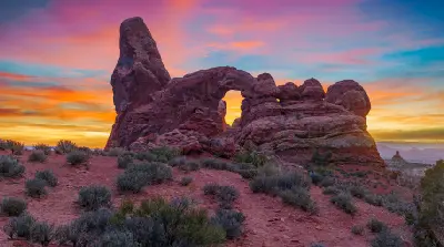 Turret Arch sandstone formation with desert vegetation at sunset in Arches National Park Utah