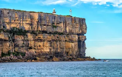 Point Perpendicular Lighthouse stands above towering layered sandstone cliffs at the northern entrance to Jervis Bay.