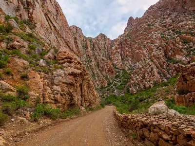 Dirt road winding through the towering canyon walls of the Red Stone Hills near Oudtshoorn in the Little Karoo, South Africa